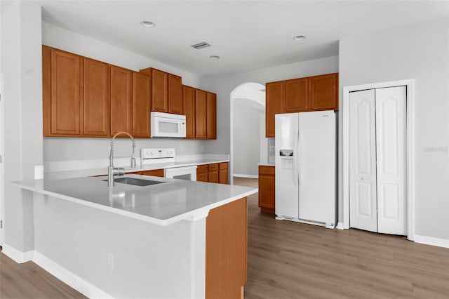 5015 58th Ter E, Bradenton, FL 34203 - kitchen featuring white appliances, arched walkways, light wood-style flooring, a peninsula, and brown cabinetry