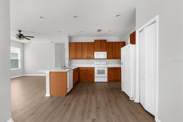 5015 58th Ter E, Bradenton, FL 34203 - kitchen featuring white appliances, a peninsula, light wood-style flooring, open floor plan, and a ceiling fan
