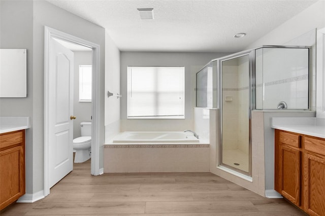 5015 58th Ter E, Bradenton, FL 34203 - bathroom with wood finished floors, vanity, a garden tub, a stall shower, and a textured ceiling