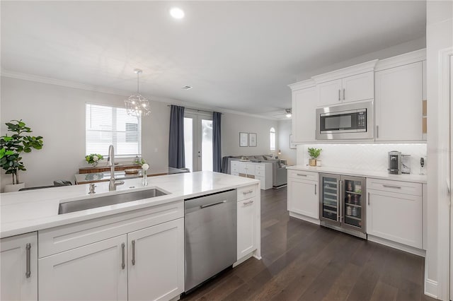 403 S Fremont Ave Unit 3, Tampa, FL 33606 - kitchen featuring appliances with stainless steel finishes, beverage cooler, ornamental molding, white cabinetry, and light countertops