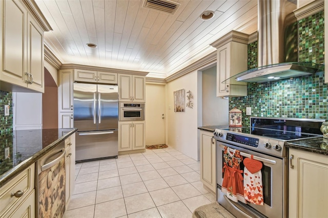 9548 141st St, Seminole, FL 33776 - kitchen featuring stainless steel appliances, cream cabinets, wall chimney range hood, light tile patterned floors, and tasteful backsplash