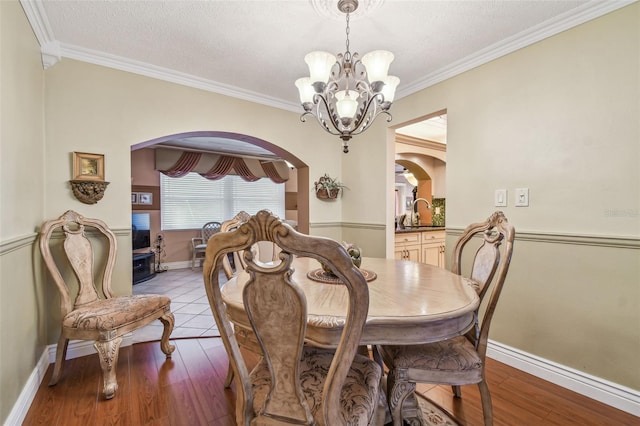 9548 141st St, Seminole, FL 33776 - dining space featuring arched walkways, a chandelier, ornamental molding, wood finished floors, and a textured ceiling