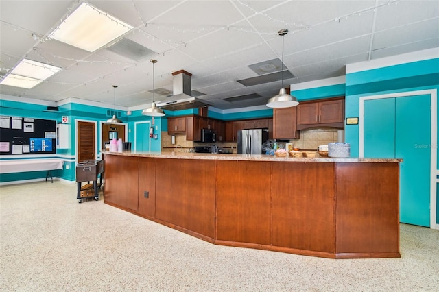 9548 141st St, Seminole, FL 33776 - kitchen with appliances with stainless steel finishes, a drop ceiling, dark speckled floor, brown cabinetry, and hanging light fixtures
