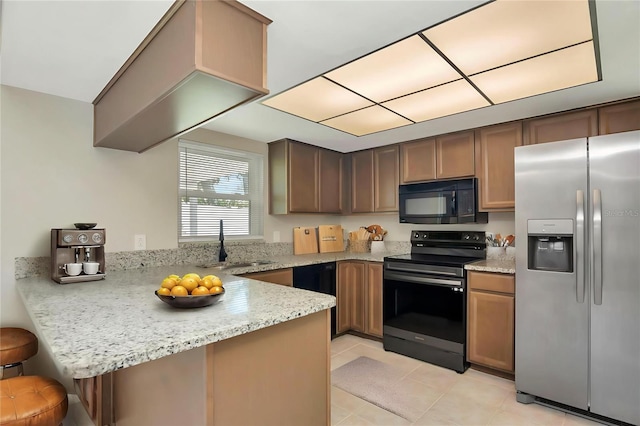 1621 Crossridge Dr, Brandon, FL 33510 - kitchen featuring black appliances, a peninsula, a kitchen bar, light tile patterned floors, and light stone countertops