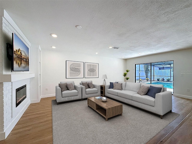 603 Ivey Ln, Tarpon Springs, FL 34689 - living area featuring wood finished floors, a textured ceiling, recessed lighting, and a glass covered fireplace