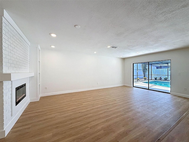 603 Ivey Ln, Tarpon Springs, FL 34689 - unfurnished living room with wood finished floors, a textured ceiling, recessed lighting, and a fireplace
