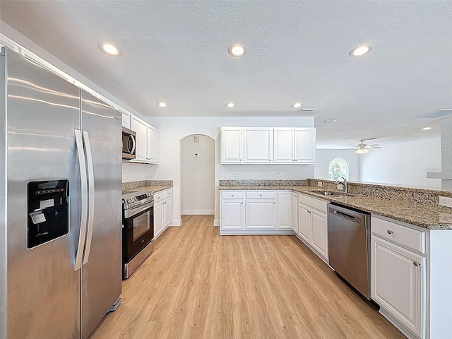 603 Ivey Ln, Tarpon Springs, FL 34689 - kitchen with stainless steel appliances, light wood-style floors, white cabinets, a peninsula, and a ceiling fan