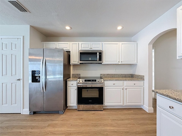 603 Ivey Ln, Tarpon Springs, FL 34689 - kitchen with appliances with stainless steel finishes, arched walkways, white cabinets, light wood-style flooring, and recessed lighting