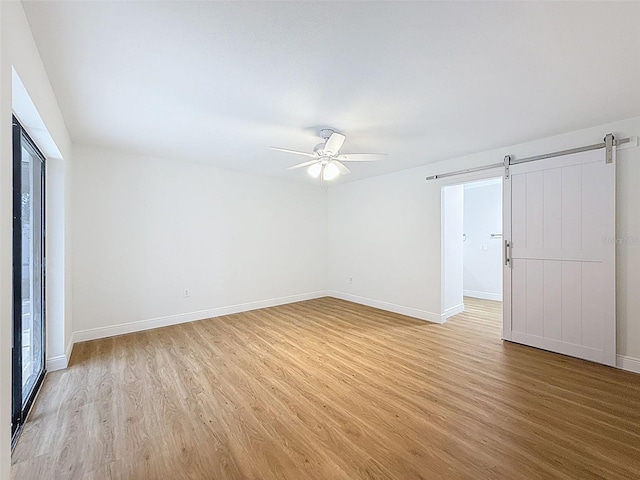 603 Ivey Ln, Tarpon Springs, FL 34689 - unfurnished room featuring a barn door, light wood finished floors, and a ceiling fan