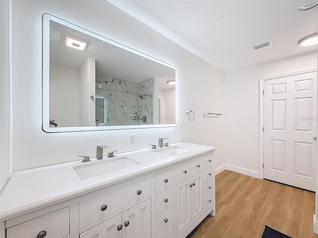 603 Ivey Ln, Tarpon Springs, FL 34689 - full bathroom with a marble finish shower, double vanity, and wood finished floors