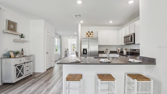 4338 Sand Dollar Way, Zephyrhills, FL 33541 - kitchen featuring stainless steel appliances, dark countertops, a peninsula, a breakfast bar area, and light wood-type flooring