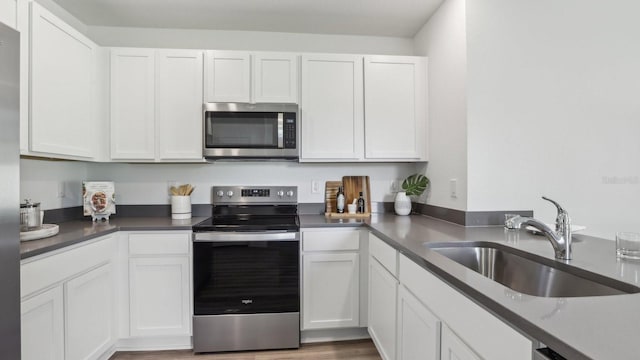4338 Sand Dollar Way, Zephyrhills, FL 33541 - kitchen with stainless steel appliances, white cabinetry, light wood-type flooring, and dark countertops