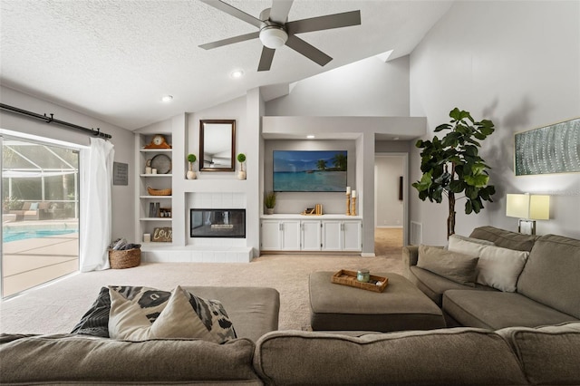 17311 Carriage Way, Odessa, FL 33556 - carpeted living area with lofted ceiling, a ceiling fan, built in features, a tiled fireplace, and a textured ceiling