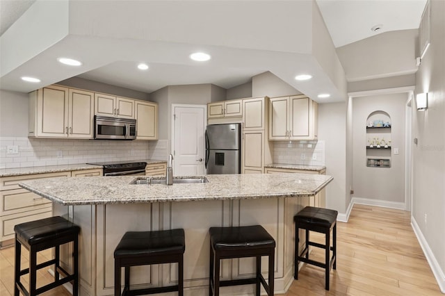 17311 Carriage Way, Odessa, FL 33556 - kitchen featuring appliances with stainless steel finishes, decorative backsplash, light wood finished floors, recessed lighting, and a breakfast bar area