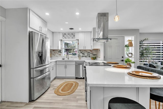 1384 S Hillcrest Ave, Clearwater, FL 33756 - kitchen with appliances with stainless steel finishes, island range hood, a peninsula, tasteful backsplash, and light wood-style floors