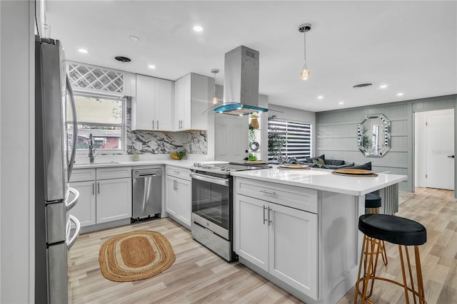 1384 S Hillcrest Ave, Clearwater, FL 33756 - kitchen with stainless steel appliances, island range hood, a peninsula, light countertops, and light wood-type flooring
