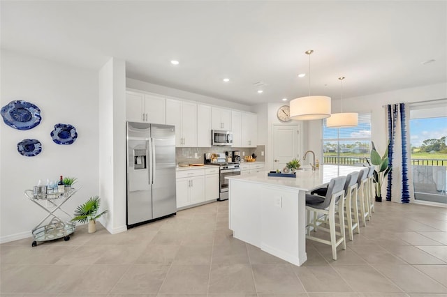 43250 Water Bird Way Unit 5921, Punta Gorda, FL 33982 - kitchen with stainless steel appliances, light countertops, decorative backsplash, a breakfast bar area, and light tile patterned floors