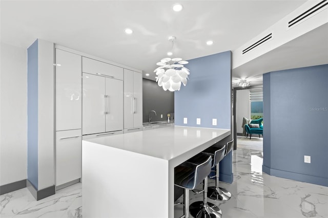 5153 Isla Key Blvd S Unit 415, Saint Petersburg, FL 33715 - kitchen featuring modern cabinets, light marble finish floors, recessed lighting, a breakfast bar area, and white cabinetry
