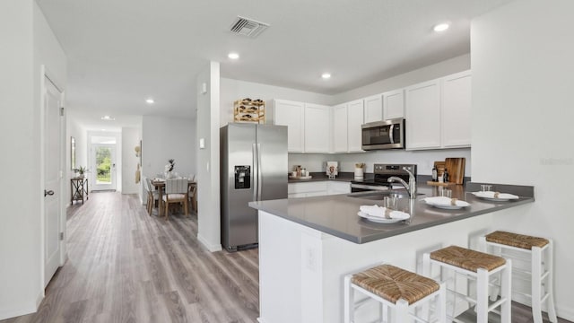 4319 Sand Dollar Way, Zephyrhills, FL 33541 - kitchen with stainless steel appliances, dark countertops, a peninsula, white cabinets, and a kitchen bar