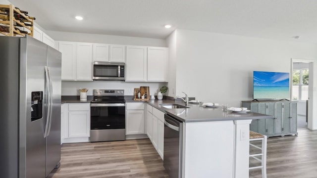 4319 Sand Dollar Way, Zephyrhills, FL 33541 - kitchen with stainless steel appliances, a peninsula, light wood-style flooring, white cabinets, and a breakfast bar area