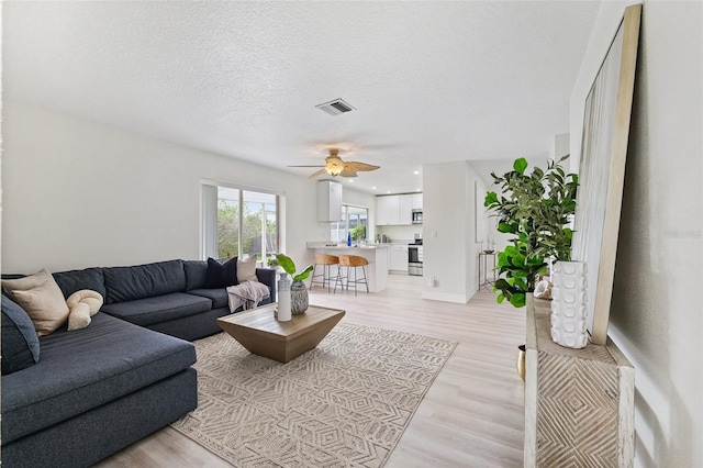 6521 Bimini Ct, Apollo Beach, FL 33572 - living area with ceiling fan, light wood-style flooring, and a textured ceiling