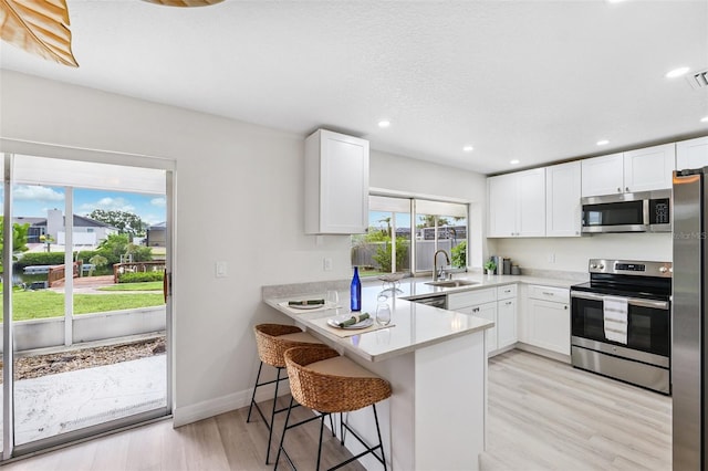 6521 Bimini Ct, Apollo Beach, FL 33572 - kitchen featuring stainless steel appliances, light wood-type flooring, white cabinets, a peninsula, and recessed lighting