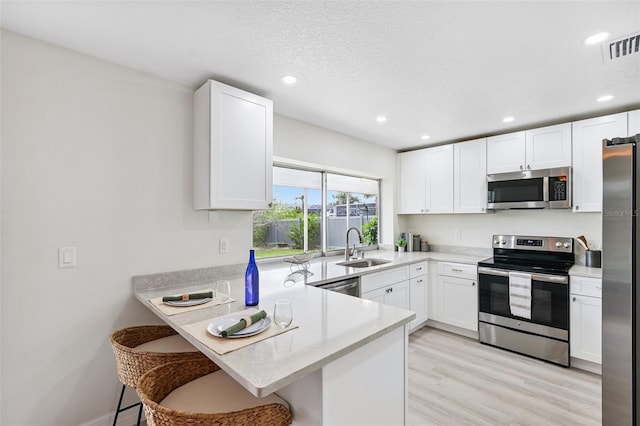 6521 Bimini Ct, Apollo Beach, FL 33572 - kitchen with appliances with stainless steel finishes, white cabinetry, a peninsula, light countertops, and recessed lighting