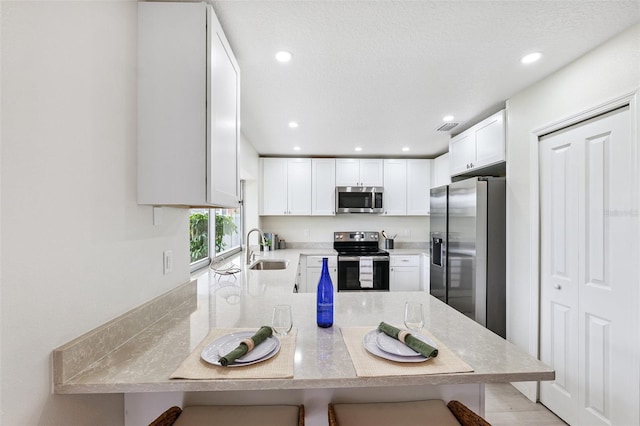 6521 Bimini Ct, Apollo Beach, FL 33572 - kitchen with appliances with stainless steel finishes, a peninsula, a kitchen bar, white cabinets, and recessed lighting
