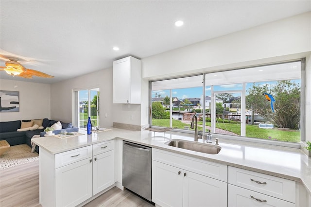 6521 Bimini Ct, Apollo Beach, FL 33572 - kitchen featuring dishwasher, a peninsula, white cabinetry, light countertops, and light wood-style flooring