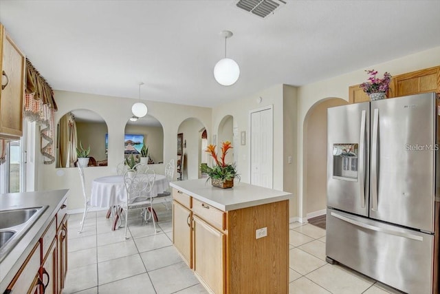 10437 River Bream Dr, Riverview, FL 33569 - kitchen featuring stainless steel fridge with ice dispenser, light tile patterned flooring, hanging light fixtures, arched walkways, and a center island