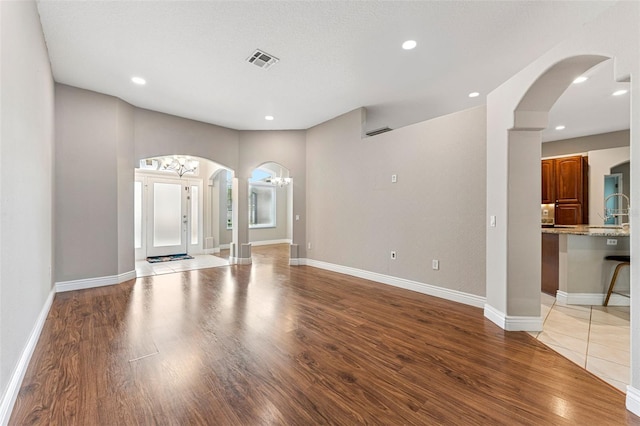 25946 Buckthorn Ave, Land O Lakes, FL 34639 - unfurnished living room with light wood-style floors, a chandelier, arched walkways, and recessed lighting