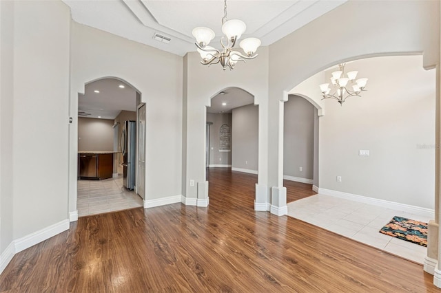 25946 Buckthorn Ave, Land O Lakes, FL 34639 - spare room featuring a chandelier, wood finished floors, and arched walkways