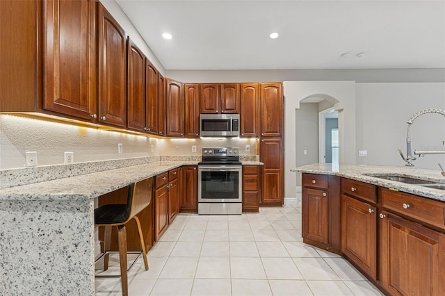 25946 Buckthorn Ave, Land O Lakes, FL 34639 - kitchen with appliances with stainless steel finishes, arched walkways, light stone countertops, light tile patterned flooring, and recessed lighting