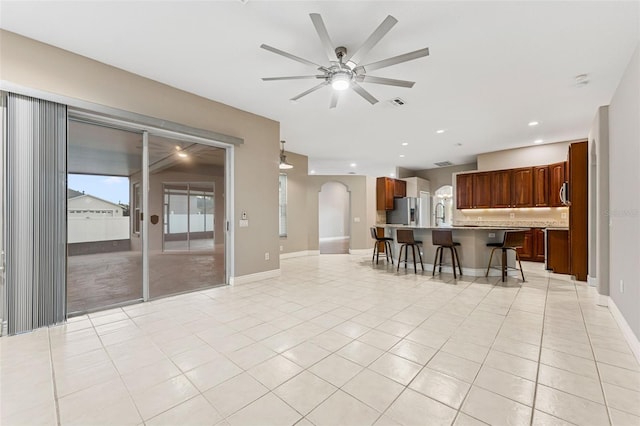 25946 Buckthorn Ave, Land O Lakes, FL 34639 - kitchen with a breakfast bar, stainless steel fridge, ceiling fan, arched walkways, and light tile patterned flooring