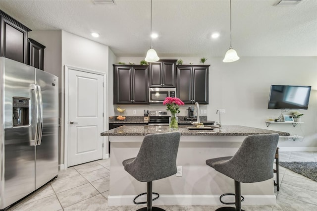 6825 Citrus Creek Ln, Tampa, FL 33625 - kitchen with stainless steel appliances, a kitchen breakfast bar, a textured ceiling, dark stone counters, and hanging light fixtures