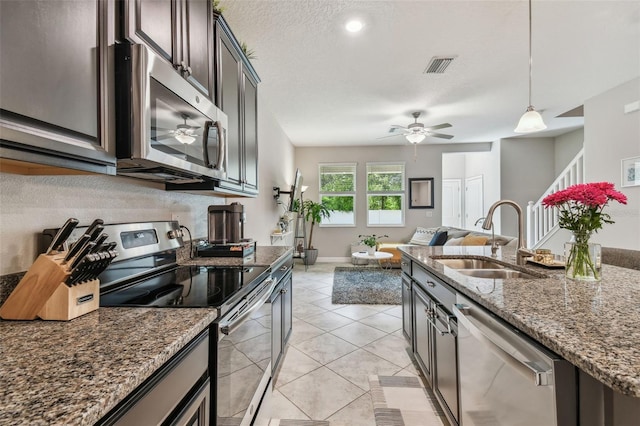 6825 Citrus Creek Ln, Tampa, FL 33625 - kitchen featuring appliances with stainless steel finishes, decorative light fixtures, dark stone countertops, a ceiling fan, and open floor plan