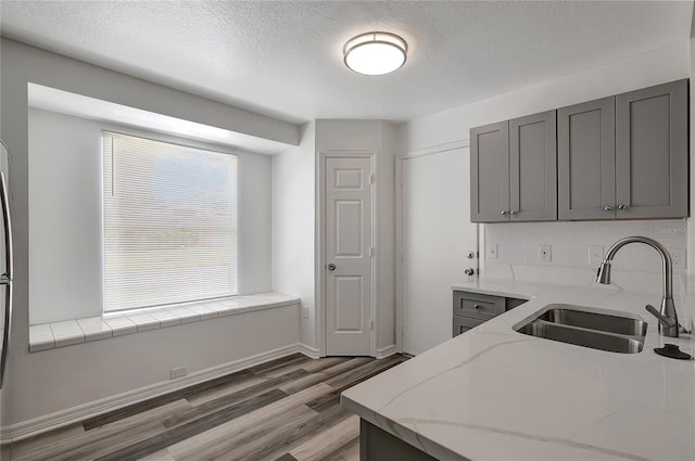 4129 Marlow Loop, Land O Lakes, FL 34639 - kitchen with light wood-style flooring, gray cabinetry, a textured ceiling, light stone countertops, and tasteful backsplash