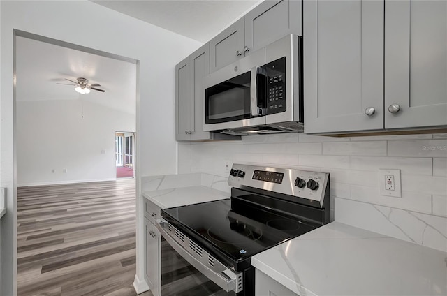 4129 Marlow Loop, Land O Lakes, FL 34639 - kitchen featuring stainless steel appliances, gray cabinetry, light wood-style floors, a ceiling fan, and tasteful backsplash