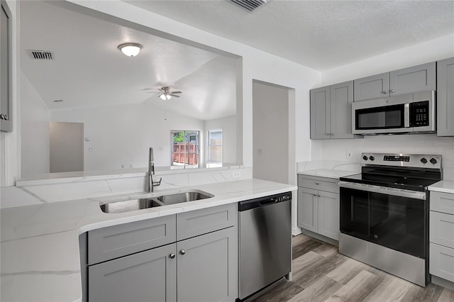 4129 Marlow Loop, Land O Lakes, FL 34639 - kitchen featuring stainless steel appliances, gray cabinets, light wood finished floors, a ceiling fan, and a textured ceiling