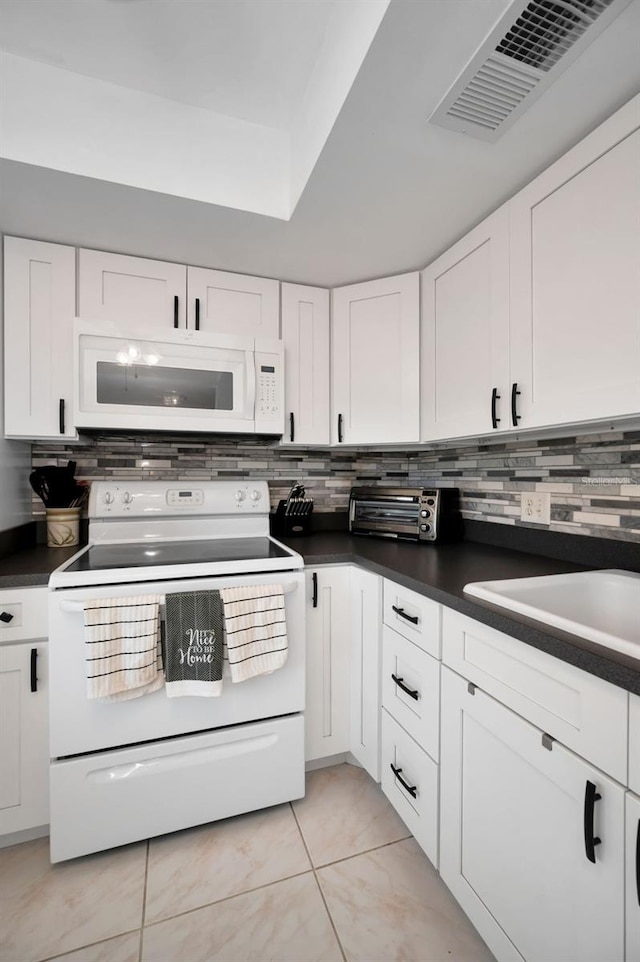 960 Virginia St Unit 204, Dunedin, FL 34698 - kitchen featuring white appliances, dark countertops, tasteful backsplash, and white cabinets