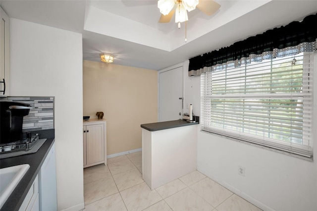 960 Virginia St Unit 204, Dunedin, FL 34698 - kitchen with dark countertops, a ceiling fan, a tray ceiling, and light tile patterned floors
