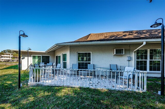960 Virginia St Unit 204, Dunedin, FL 34698 - rear view of house with stucco siding, a patio, a yard, roof with shingles, and outdoor dining area