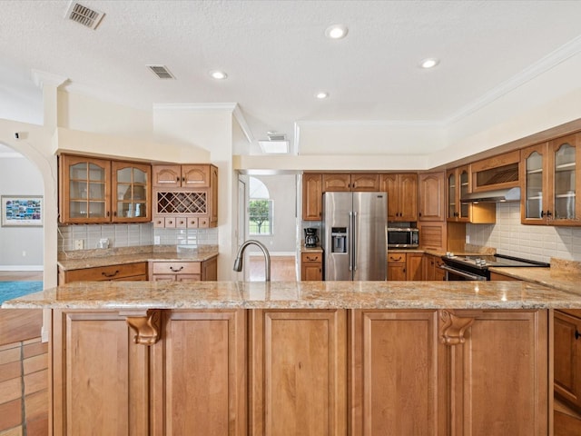 18803 Misty Shores Ln, Lutz, FL 33548 - kitchen featuring stainless steel appliances, ornamental molding, brown cabinets, a kitchen bar, and tasteful backsplash