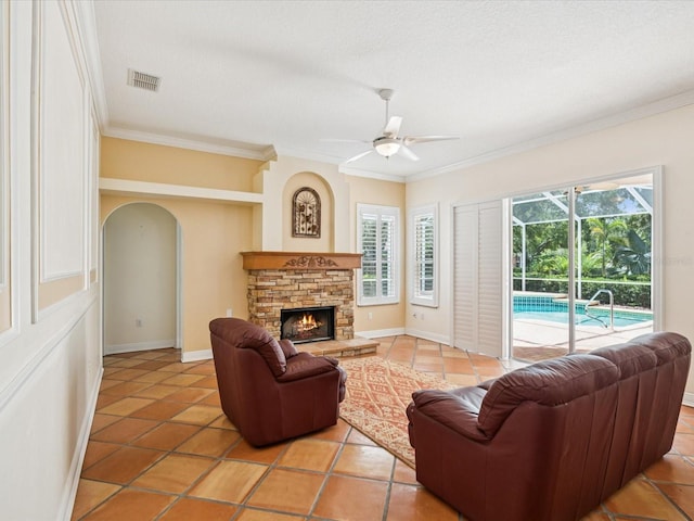 18803 Misty Shores Ln, Lutz, FL 33548 - living area featuring arched walkways, ornamental molding, ceiling fan, light tile patterned flooring, and a stone fireplace