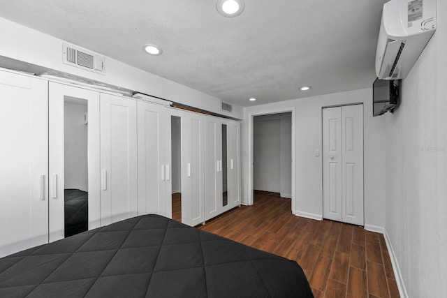 7003 Yule Ln, Tampa, FL 33637 - unfurnished bedroom featuring multiple closets, dark wood-type flooring, a wall mounted AC, and recessed lighting