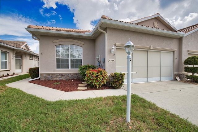 8354 Palmetto Ct, Englewood, FL 34224 - view of front of home featuring concrete driveway, stucco siding, an attached garage, a tiled roof, and stone siding