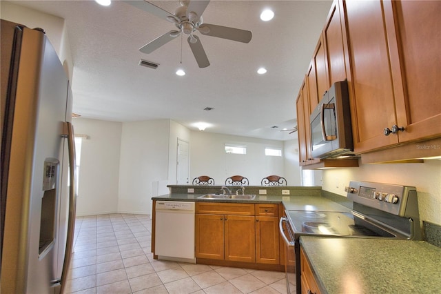 8354 Palmetto Ct, Englewood, FL 34224 - kitchen featuring stainless steel appliances, brown cabinets, a peninsula, light tile patterned floors, and recessed lighting