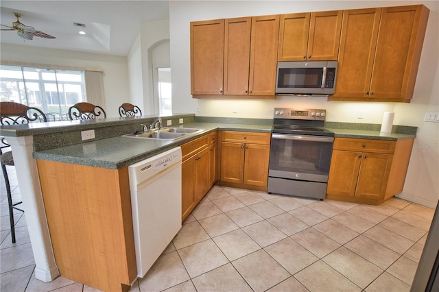 8354 Palmetto Ct, Englewood, FL 34224 - kitchen featuring appliances with stainless steel finishes, a peninsula, dark countertops, light tile patterned floors, and recessed lighting