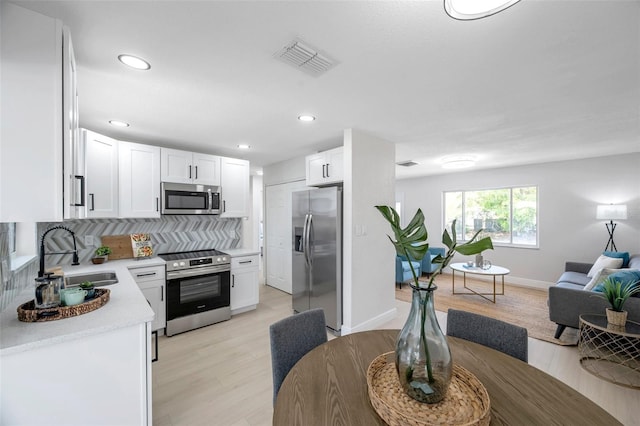 8045 Colton Dr, Port Richey, FL 34668 - kitchen with appliances with stainless steel finishes, open floor plan, light countertops, tasteful backsplash, and white cabinetry