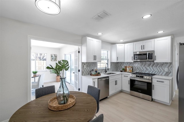 8045 Colton Dr, Port Richey, FL 34668 - kitchen featuring stainless steel appliances, tasteful backsplash, white cabinetry, and recessed lighting